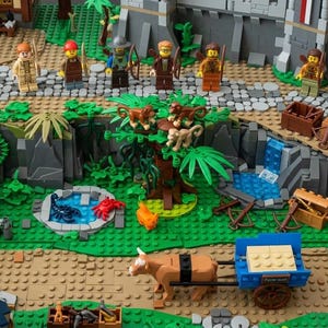 May include: A detailed LEGO construction set featuring a medieval village scene with stone buildings, a cobblestone path, and a central jungle area with a tree, monkeys, a small pond with a blue scorpion and red crab, and a brown ox pulling a blue cart.