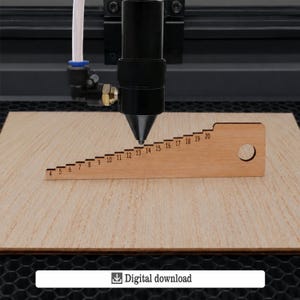 Può includere: Uno strumento di calibrazione per incisione laser in legno con numeri da 4 a 20, per misurazioni precise. Lo strumento è posizionato sotto una testa di macchina per incisione laser. Il testo "Digital download" è incluso.