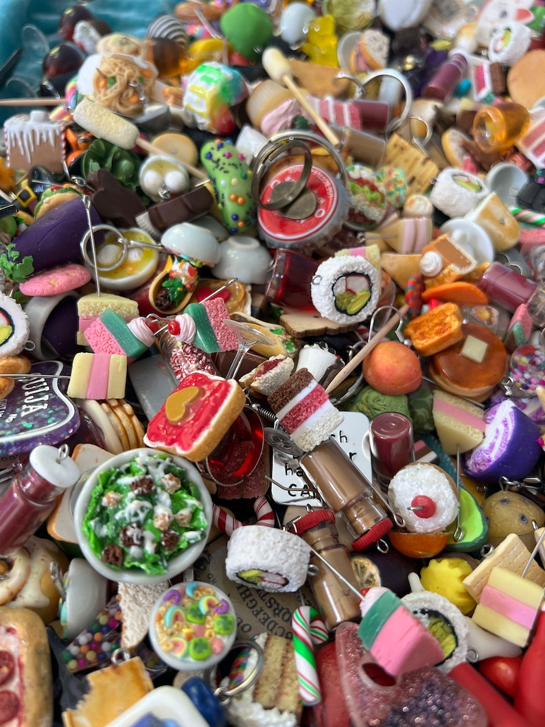 Pile of assorted miniature foods made with polymer clay. Features sushi, tacos, cupcakes, Halloween and Christmas foods and also miniature video game items.