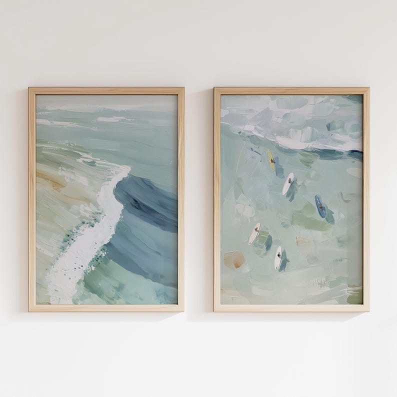 Puede incluir: Dos impresiones art&iacute;sticas abstractas enmarcadas. La impresi&oacute;n de la izquierda representa una ola rompiendo en la orilla, con tonos azules, verdes y blancos. La impresi&oacute;n de la derecha muestra surfistas en el oc&eacute;ano, con una paleta de colores similar. Ambas impresiones est&aacute;n en marcos de madera clara.