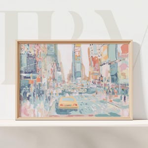 以下が含まれることがあります： 黄色いタクシーのある街の通りのシーンを描いた、額入りのアートプリント。 このアートワークは、青、ピンク、オレンジのソフトな色使いで、絵画のような効果を生み出しています。 フレームは明るい木の色です。