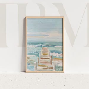 以下が含まれることがあります： 額装されたビーチシーンのアートプリント。絵画は、海に伸びる木製の桟橋、波、水色の空を描いています。アートワークは木製のフレームに入っており、海岸のテーマを作り出しています。