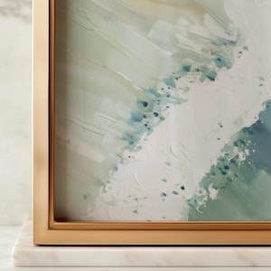 Puede incluir: Impresi&oacute;n art&iacute;stica abstracta en un marco dorado. La obra de arte presenta un dise&ntilde;o texturizado y en capas con tonos de blanco, verde y azul. El marco se asienta sobre una base de m&aacute;rmol blanco, agregando un toque de elegancia.