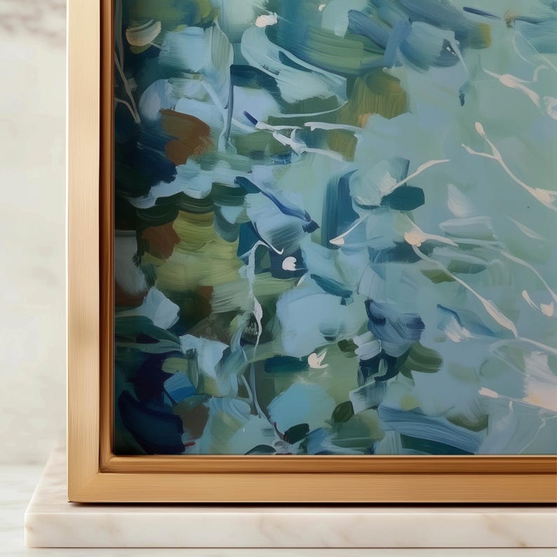 May include: Abstract art print with a gold frame, featuring brushstrokes in shades of blue, green, and white. The artwork is mounted on a white marble base, creating a modern and elegant aesthetic.