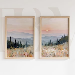 Puede incluir: Dos pinturas de paisaje enmarcadas. Cada una presenta una cordillera bajo un cielo de atardecer pastel. El primer plano muestra un campo con pinceladas coloridas y árboles verde oscuro. Los marcos son de madera clara.