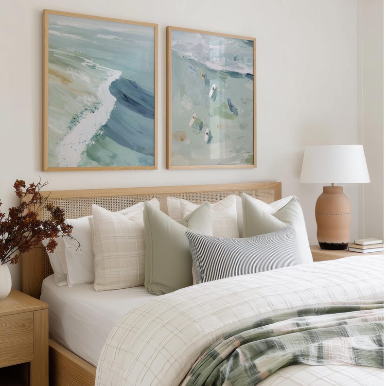 Puede incluir: Decoraci&oacute;n de dormitorio con dos pinturas abstractas enmarcadas de olas en tonos azules y verdes. La cama tiene un cabecero de madera clara, almohadas blancas y un edred&oacute;n a cuadros. Una l&aacute;mpara con base de terracota est&aacute; sobre la mesita de noche.