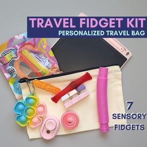 May include: A beige travel pouch with a zip closure, containing seven sensory fidget toys. The pouch is labelled "TRAVEL FIDGET KIT PERSONALIZED TRAVEL BAG". The toys include a pop-it, a fidget spinner, a stress ball, a stretchy band, a textured tube, and a small set of stacking blocks. The text "7 SENSORY FIDGETS" is visible in the lower right corner of the image.