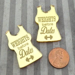 May include: Two gold mirror acrylic tank top shapes with the text "Weights before Dates" and a dumbbell symbol.