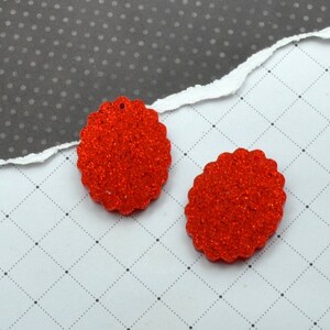 Op de afbeelding: Twee rode glittercirkelversieringen met gegolfde randen.