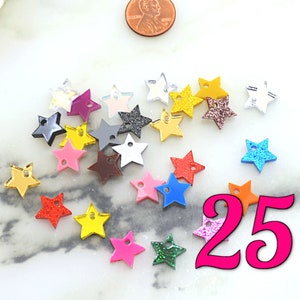 May include: A collection of 25 assorted acrylic star charms with a hole for hanging. The stars are in various colours, including red, blue, green, yellow, orange, pink, purple, and silver. Some stars have glitter.