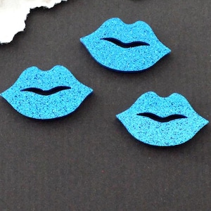 Op de afbeelding: Drie blauwe glitter lippen uitsparingen. De lippen zijn ongeveer zo groot als een Nederlandse cent.