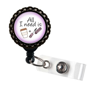 May include: A black and silver retractable badge reel with a clear plastic strap. The reel features a circular design with the text "All I need is:" and illustrations of a coffee cup and mascara. The background is a gradient of white to purple.