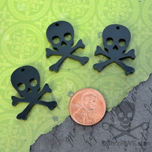 Può includere: Tre ciondoli in acrilico nero a forma di teschio e ossa incrociate. I ciondoli sono circa delle dimensioni di una moneta da un centesimo di euro.