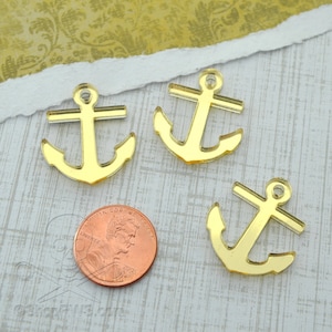 Può includere: Tre ciondoli a forma di ancora in acrilico dorato a specchio. I ciondoli sono circa delle dimensioni di una moneta da un centesimo di dollaro americano.