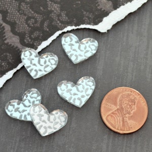Op de afbeelding: Vijf lichtblauwe hartvormige glazen cabochons met een wit luipaardmotief. De cabochons zijn ongeveer zo groot als een Nederlandse cent.