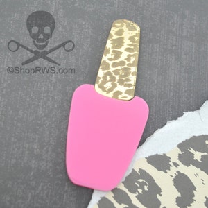 Op de afbeelding: Een roze nagellak flesje met een gouden dop met luipaardprint. De fles is gemaakt van acryl en is een leuk en eigenzinnig accessoire.