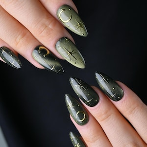 Puede incluir: Uñas almendradas verde oliva con diseños celestiales dorados. Cada uña presenta una luna creciente dorada, estrellas y pequeños puntos. Las uñas tienen un acabado brillante, creando un aspecto elegante y único.