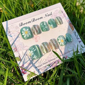 This nail set showcases a refreshing mint green base with delicate daisy accents, complemented by shimmering gold details. The design exudes a fresh and natural vibe, perfect for a cheerful and uplifting look.