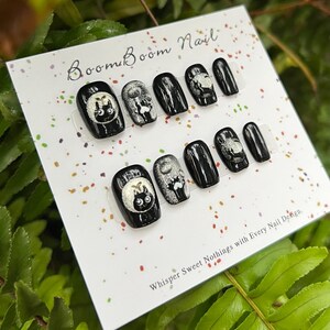 This nail set features a playful black base adorned with whimsical silver characters and patterns, adding a fun and mysterious vibe. Perfect for those who love unique, eye-catching designs with a touch of charm.