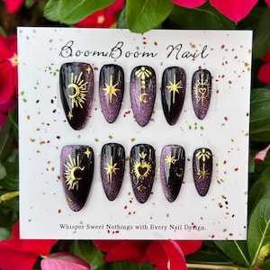 This nail set features a deep green base with intricate gold celestial designs, including stars, moons, and suns, creating a mystical and elegant look.