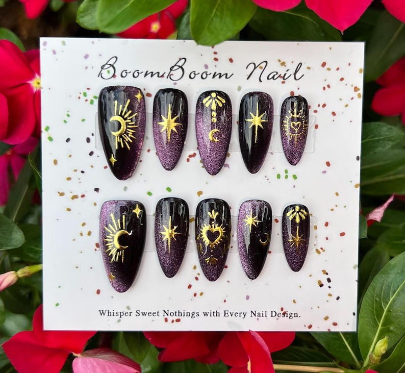 This nail set features a deep green base with intricate gold celestial designs, including stars, moons, and suns, creating a mystical and elegant look.