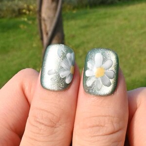 This nail set showcases a refreshing mint green base with delicate daisy accents, complemented by shimmering gold details. The design exudes a fresh and natural vibe, perfect for a cheerful and uplifting look.