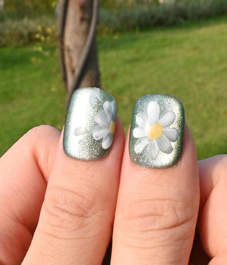 This nail set showcases a refreshing mint green base with delicate daisy accents, complemented by shimmering gold details. The design exudes a fresh and natural vibe, perfect for a cheerful and uplifting look.