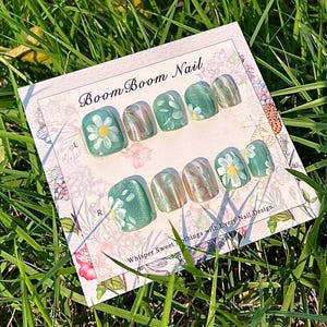 This nail set showcases a refreshing mint green base with delicate daisy accents, complemented by shimmering gold details. The design exudes a fresh and natural vibe, perfect for a cheerful and uplifting look.