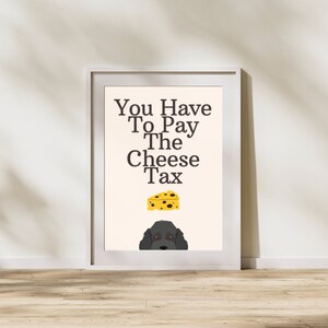 May include: A white framed print with the text "You Have To Pay The Cheese Tax" in black. A cartoon image of a slice of cheese and a black dog's head are below the text.