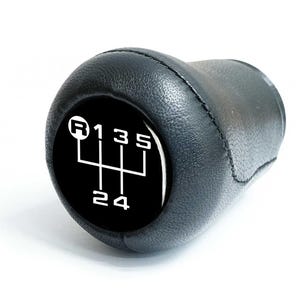 May include: Black leather gear stick knob featuring a white gear pattern on a black face. The gear pattern displays the reverse, first, third, fifth, second, and fourth gears. Designed for a manual transmission.