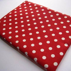 May include: A red fabric item with a white polka dot pattern. The item is rectangular and appears to be folded. The fabric has a textured appearance. The item is likely a case or cover.