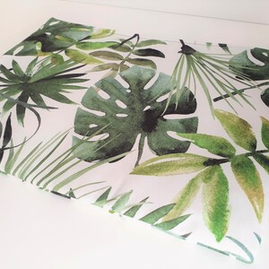 May include: White fabric with a green tropical leaf pattern. The leaves are painted in a watercolour style and include palm leaves, monstera leaves, and ferns.