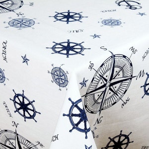 May include: White tablecloth with a nautical theme featuring blue compass and ship wheel designs. The text "YATCH" and "SAIL" are printed on the fabric.