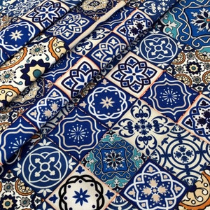May include: A close-up of a fabric with a repeating pattern of blue, white, and orange geometric tile designs. The tiles feature floral and star motifs, creating a vibrant and decorative textile.