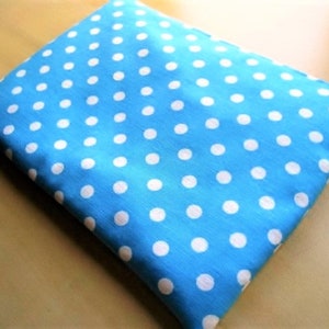 May include: A square, light blue cushion featuring a white polka dot design. The cushion is made of fabric and has a simple design. The white polka dots are evenly spaced across the surface.