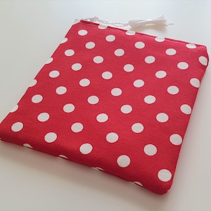 May include: Red fabric pouch with white polka dots. The pouch has a white drawstring closure.