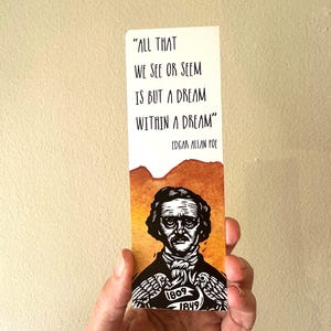 Könnte beinhalten: Ein rechteckiges Lesezeichen mit einer schwarz-weißen Illustration von Edgar Allan Poe, zwei Raben und den Jahreszahlen 1809-1849. Über dem Porträt steht der Text: "ALL THAT WE SEE OR SEEM IS BUT A DREAM WITHIN A DREAM" von Edgar Allan Poe.