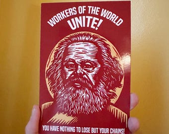 Könnte beinhalten: Rotes und weißes Plakat mit einer Holzschnitt-Illustration von Karl Marx. Das Plakat lautet "Arbeiter aller Länder, vereinigt euch! Ihr habt nichts zu verlieren als eure Ketten!"