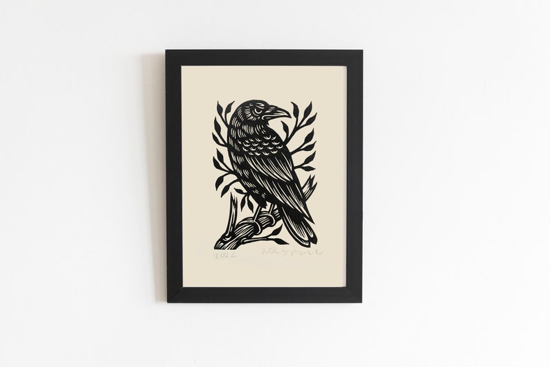 May include: Black and white print of a crow perched on a branch. The print is framed in a black frame and has a cream background.