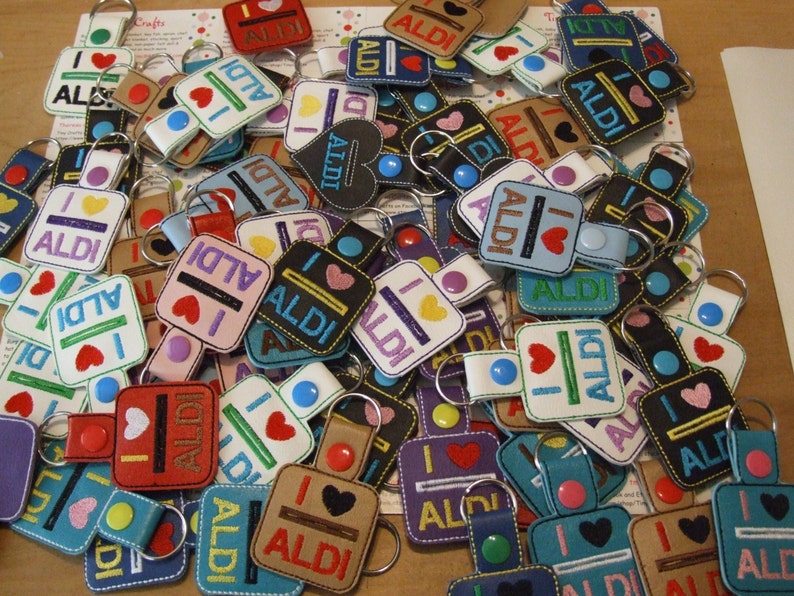 May include: A collection of colorful keychains with the text "I love ALDI" on them. The keychains are made of fabric and have a variety of designs, including hearts, stripes, and polka dots.