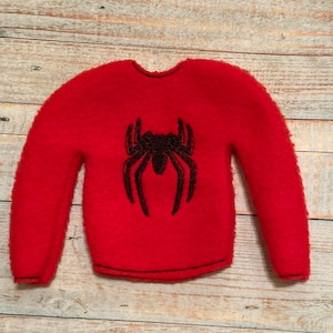 May include: A red sweater with a black spider emblem on the front. The sweater has long sleeves and a crew neck. The spider design is centered on the chest.