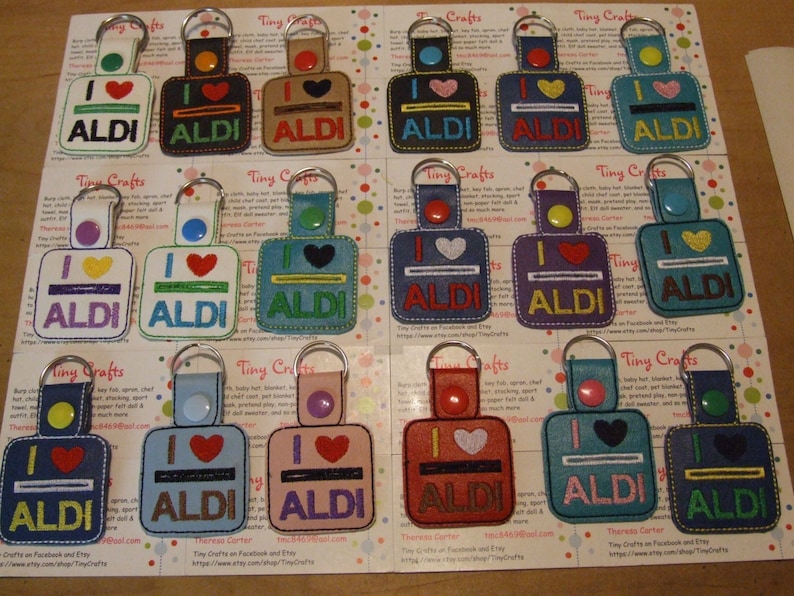 May include: A collection of 12 keychains featuring a colorful embroidered design with the text "I love ALDI". Each keychain has a different color scheme and a small heart with a line above it.