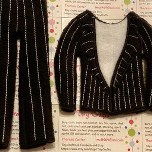 May include: A black and white striped felt suit for a doll. The suit includes a jacket and pants. The jacket has a white felt lining. The suit is made by Tiny Crafts.