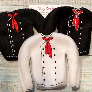 May include: Three elf-sized outfits for a Christmas elf. Two black outfits with white trim and red ties, and one white outfit with black trim and a red tie.
