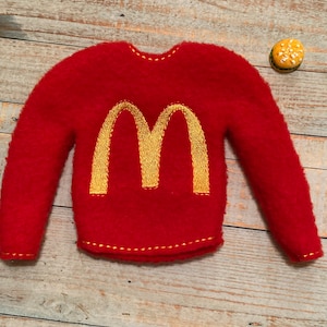 May include: Red fleece sweater with a yellow embroidered "M" on the front.