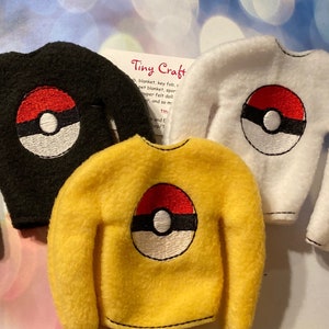 May include: Three fleece elf-sized sweaters with a Pokeball design. The sweaters are black, white, and yellow.