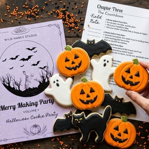 May include: A collection of Halloween-themed sugar cookies shaped like orange pumpkins, white ghosts, black bats, and a black cat, arranged next to a Wild Hares Studio party planning booklet and a printed checklist titled Chapter Three The Countdown.