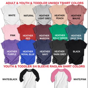 May include: A selection of unisex t-shirts in a range of colours, such as white, pink, and black. The image also features raglan shirts with 3/4 sleeves in white/black and white/pink. Text indicates the colours are for adults, youth, and toddlers.