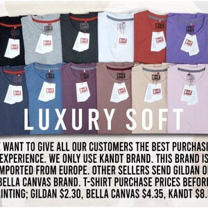 May include: An assortment of folded t-shirts in shades like black, grey, white, red, and purple. Each shirt has a tag attached. The words "LUXURY SOFT" are prominently displayed in white across the center of the image.