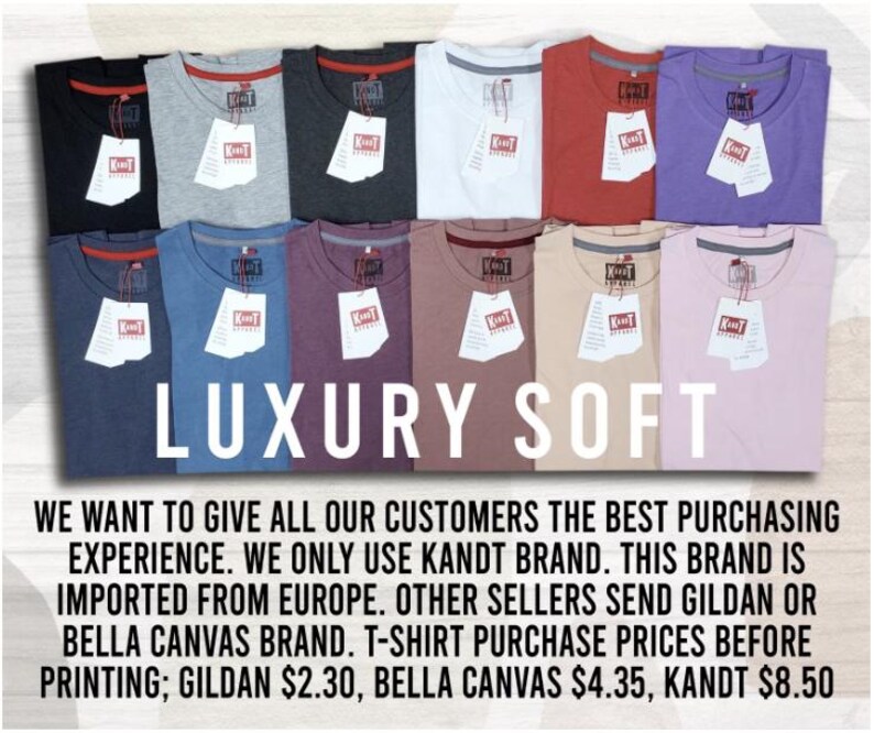 May include: An assortment of folded t-shirts in shades like black, grey, white, red, and purple. Each shirt has a tag attached. The words "LUXURY SOFT" are prominently displayed in white across the center of the image.